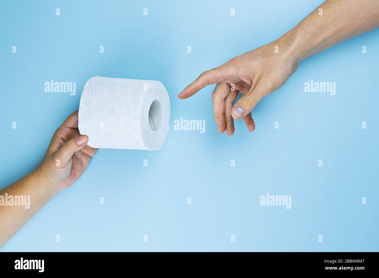 Female hand gives toilet paper roll to male hand on blue background
