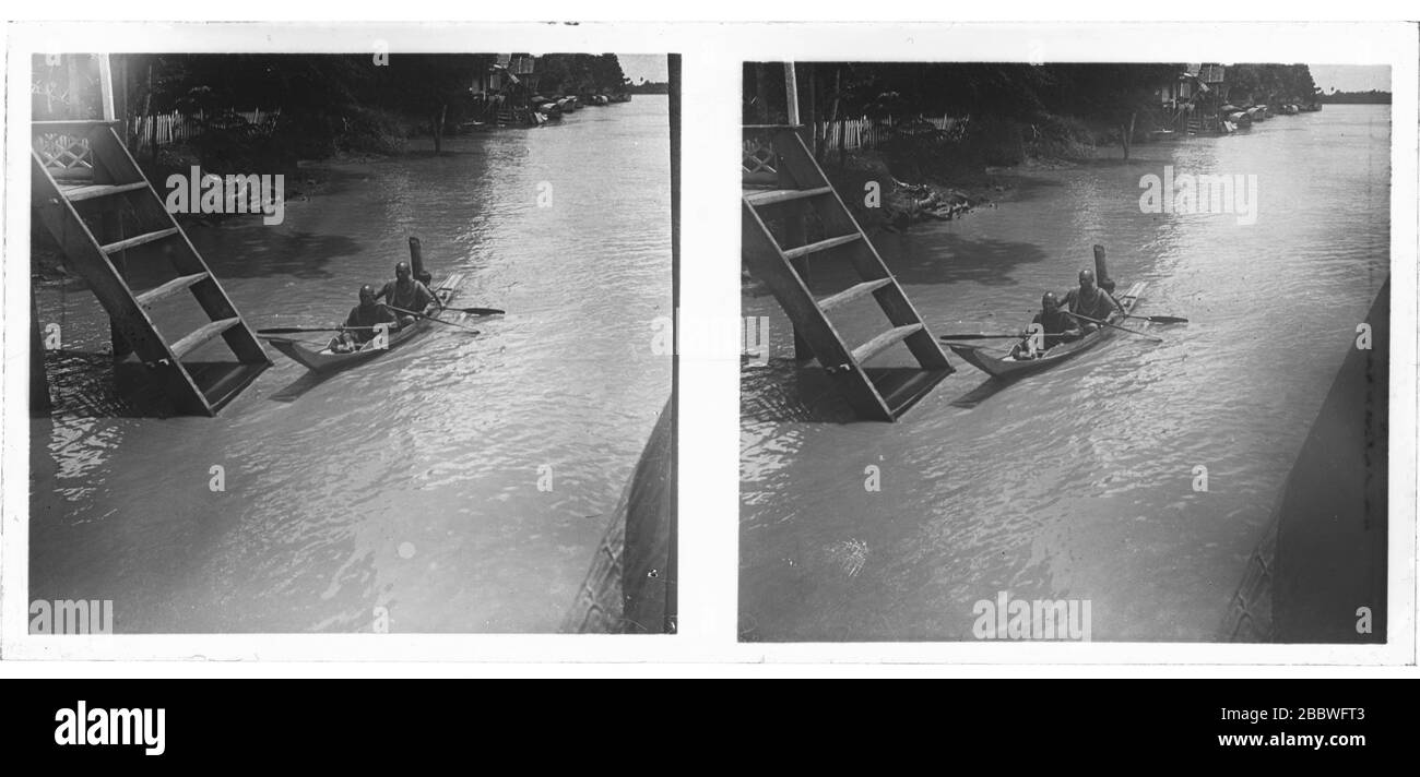 2 Buddhist monks with a boy in a traditional longtail boad paddling on the Stung Sangkae river. Stereoscopic photograph from around 1910. Picture on dry glass plate from the Herry W. Schaefer collection. Stock Photo