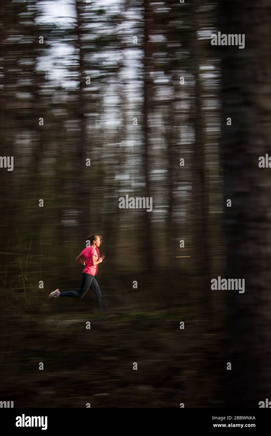 Young woman running outdoors in a forest, going fast (motion blurred ...