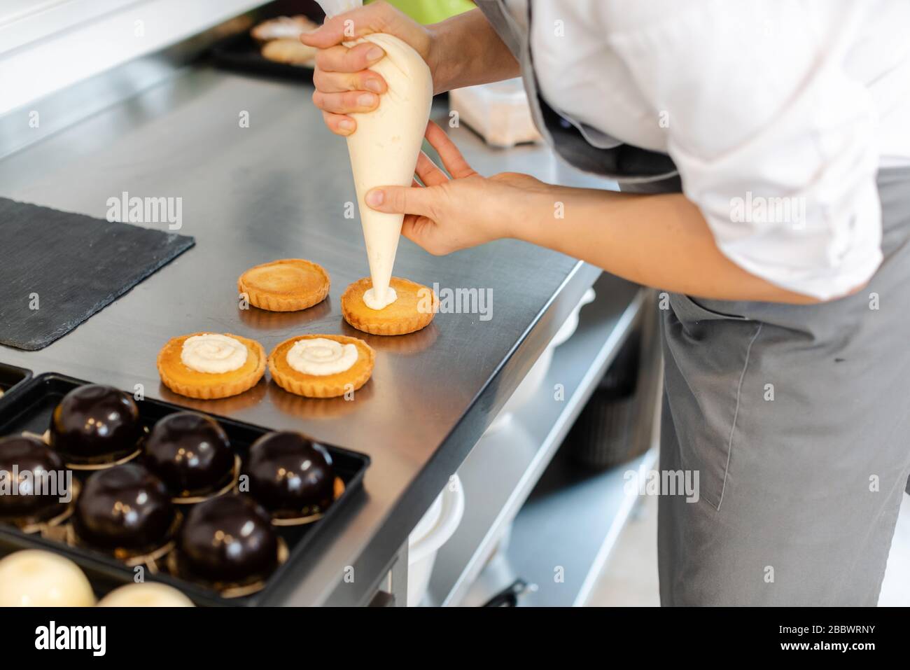Pastry chef using icing bag to put creme on cake Stock Photo