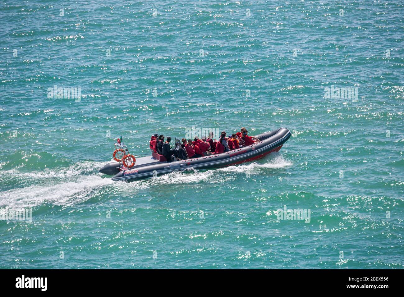 Inflatable boat with tourist sightseers on the coast west of Alporchinhas, Algarve, Portugal Stock Photo