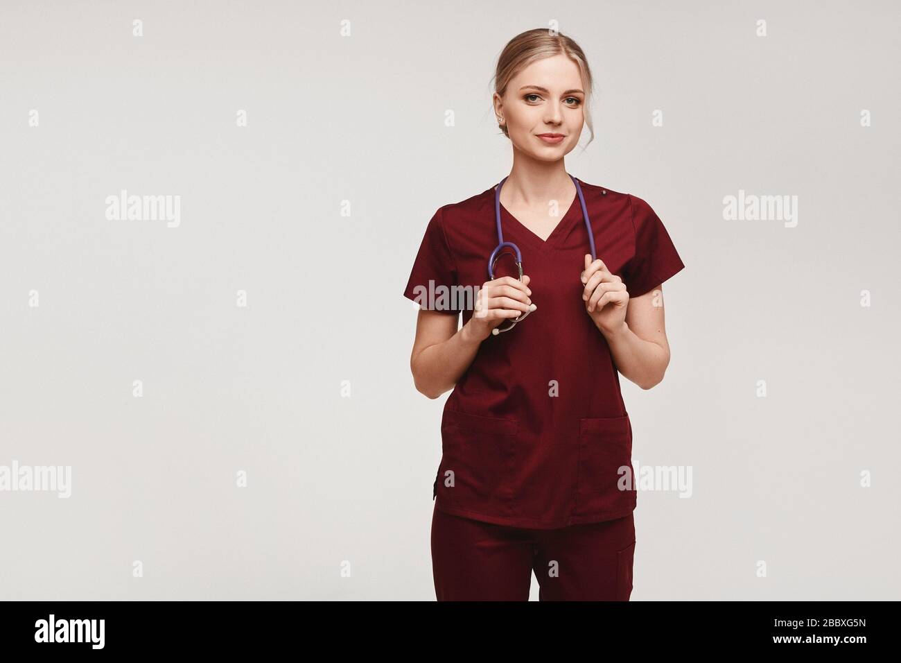 Young female doctor in medical uniform with stethoscope posing on a ...
