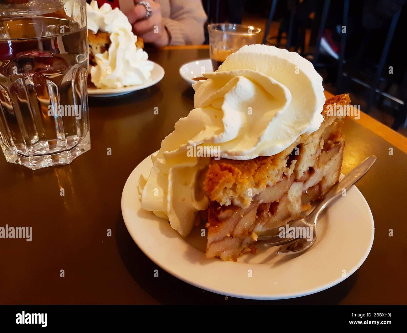 high Dutch apple pie with plenty of whipped cream on a brown wooden table  with a cup of hot tea in winter in amsterdam Stock Photo - Alamy