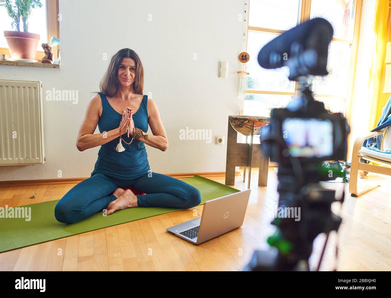 Kaufbeuren, Germany, April 01, 2020. Yoga teacher teaches customers in a online course and live streaming with computer and iphone due to the Corona virus disease (COVID-19) on April 01, 2020 in Kaufbeuren, Germany Model released © Peter Schatz / Alamy Live News Stock Photo