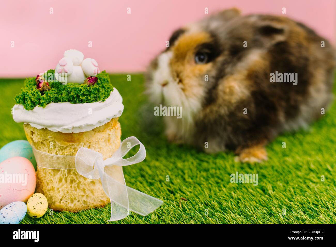 Easter bunny sits next to Easter, glazed Easter cakes. Happy easter concept. Copy space for your text. Stock Photo