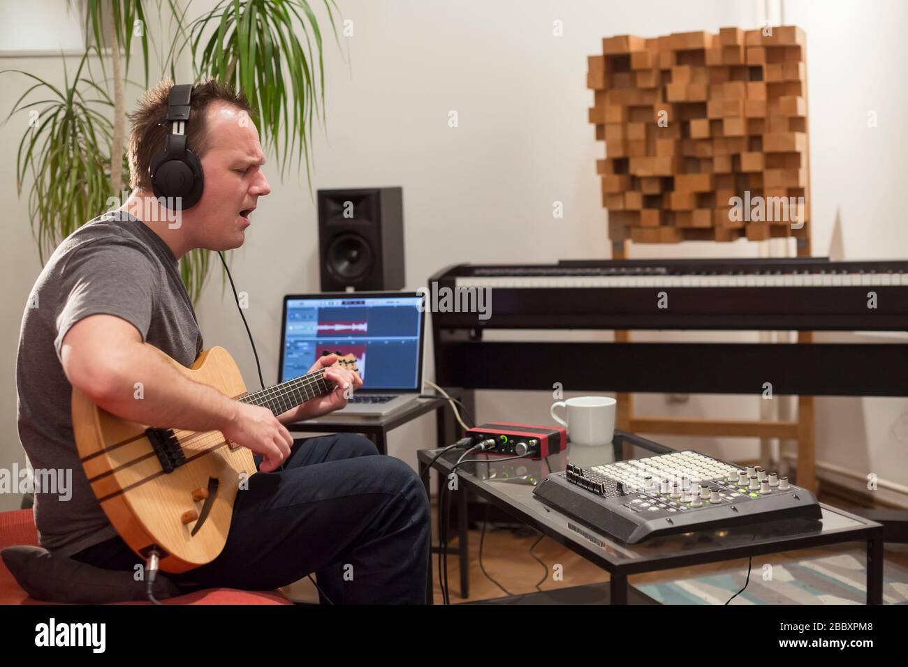 Professional musician recording electric guitar in digital studio at home.  He is surrounded with instruments and midi controller. Music production con  Stock Photo - Alamy