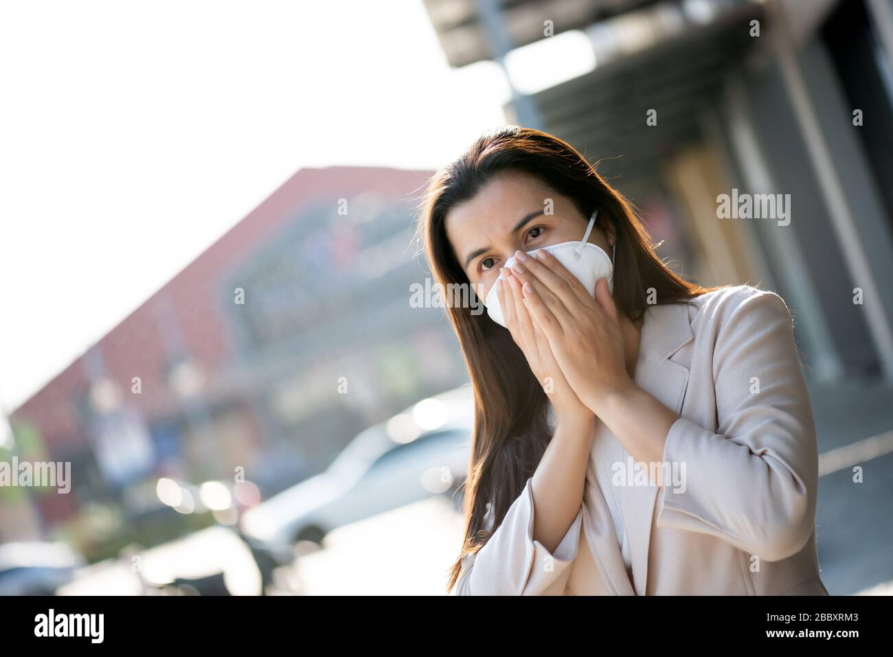 Close up of a businesswoman in a suit wearing Protective face mask and cough, get ready for Coronavirus and pm 2.5 fighting against beside road in bac Stock Photo