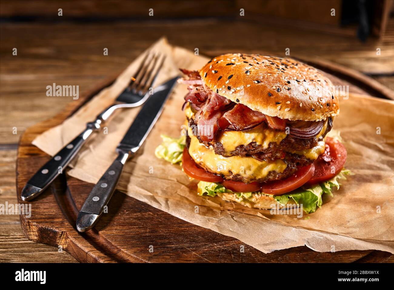 Juicy American burger, hamburger or cheeseburger with two beef patties, with sauce and basked on a black background. Concept of American fast food Stock Photo