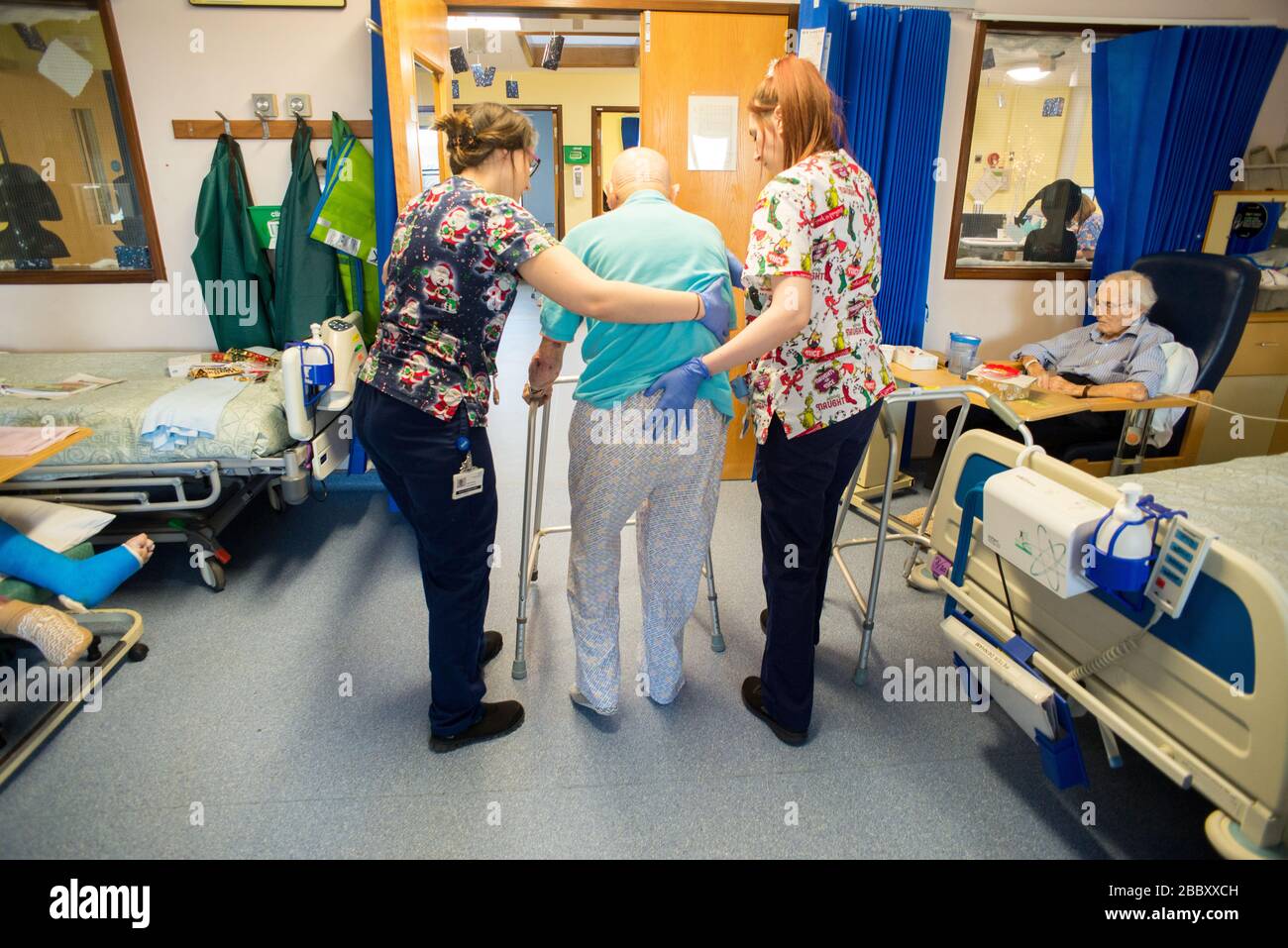 ANDOVER,HAMPSHIRE/UNITED KINGDOM- DECEMBER 25 2019:An elderly man with brain injury is being helped to walk using a walking frame,by nursing staff,sur Stock Photo