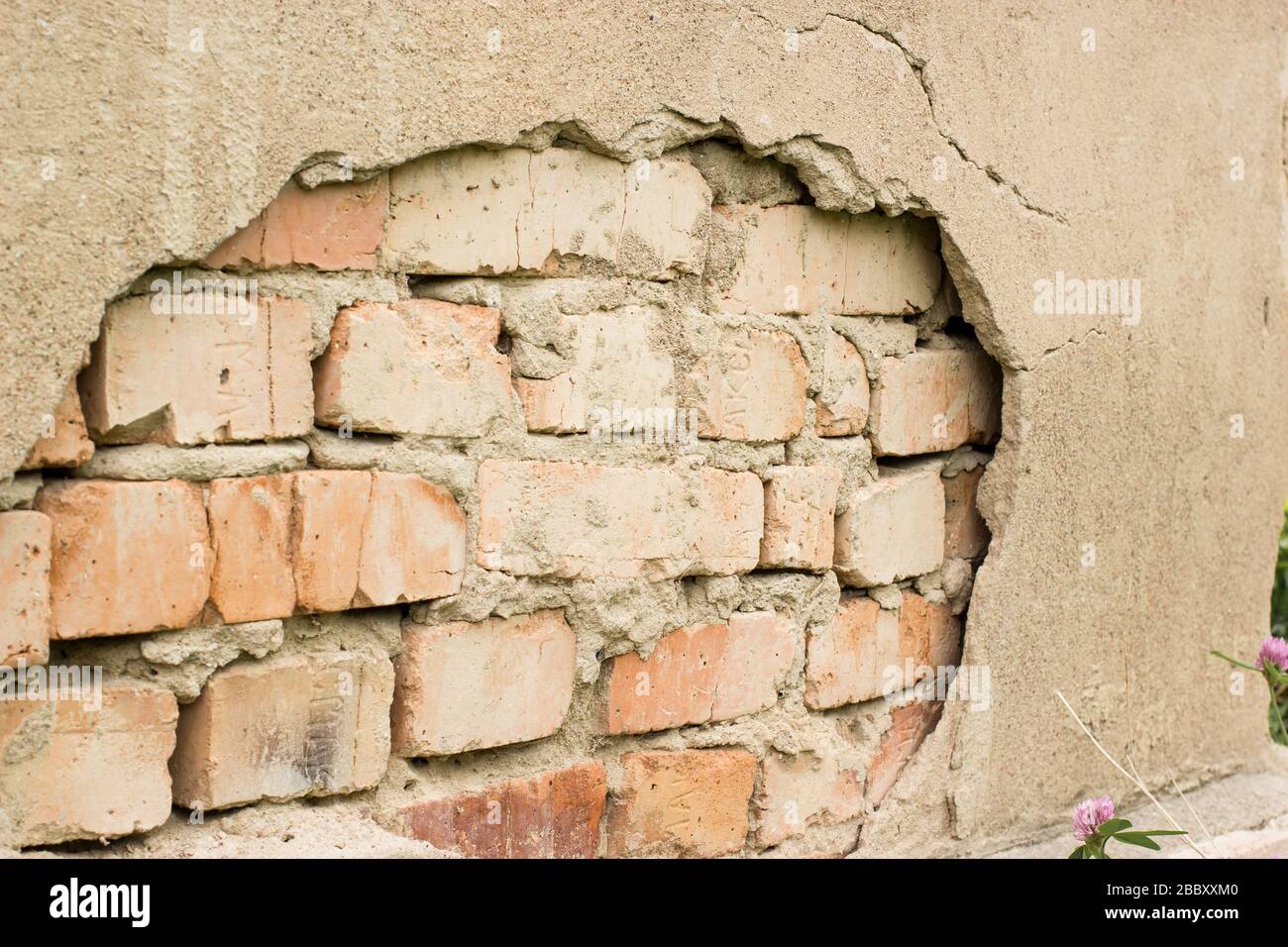 Non technology plaster. Building cracked plaster facade wall with brick. Stock Photo