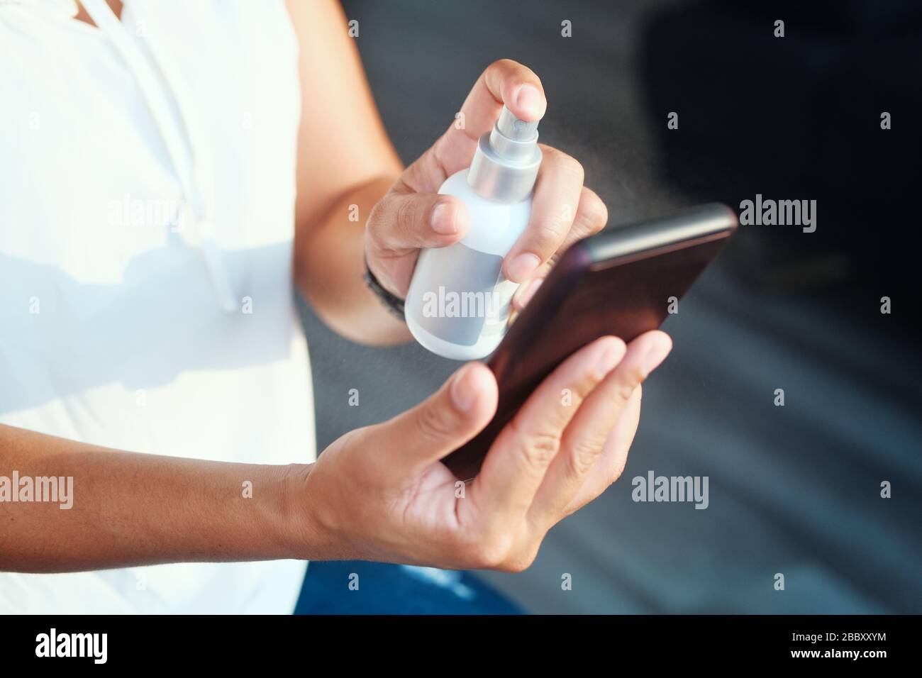 Woman Cleaning And Disinfecting Cell Phone Against Virus Stock Photo