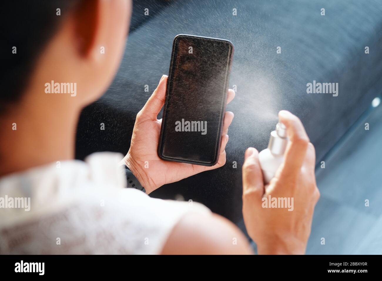 Woman Cleaning And Disinfecting Cell Phone Against Virus Stock Photo