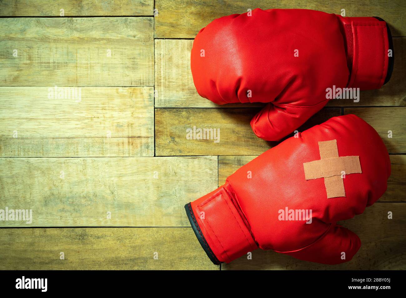 Red boxing gloves placed on wooden floor at the gym. Adhesive plaster
