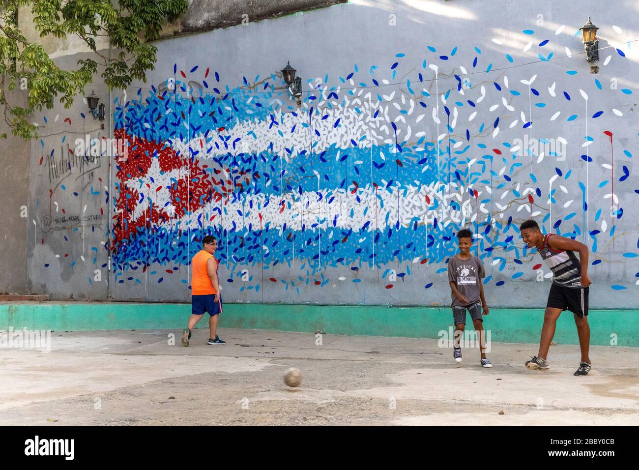 Boy playing soccer by Cuban flag street art mural, Old Havana Stock Photo