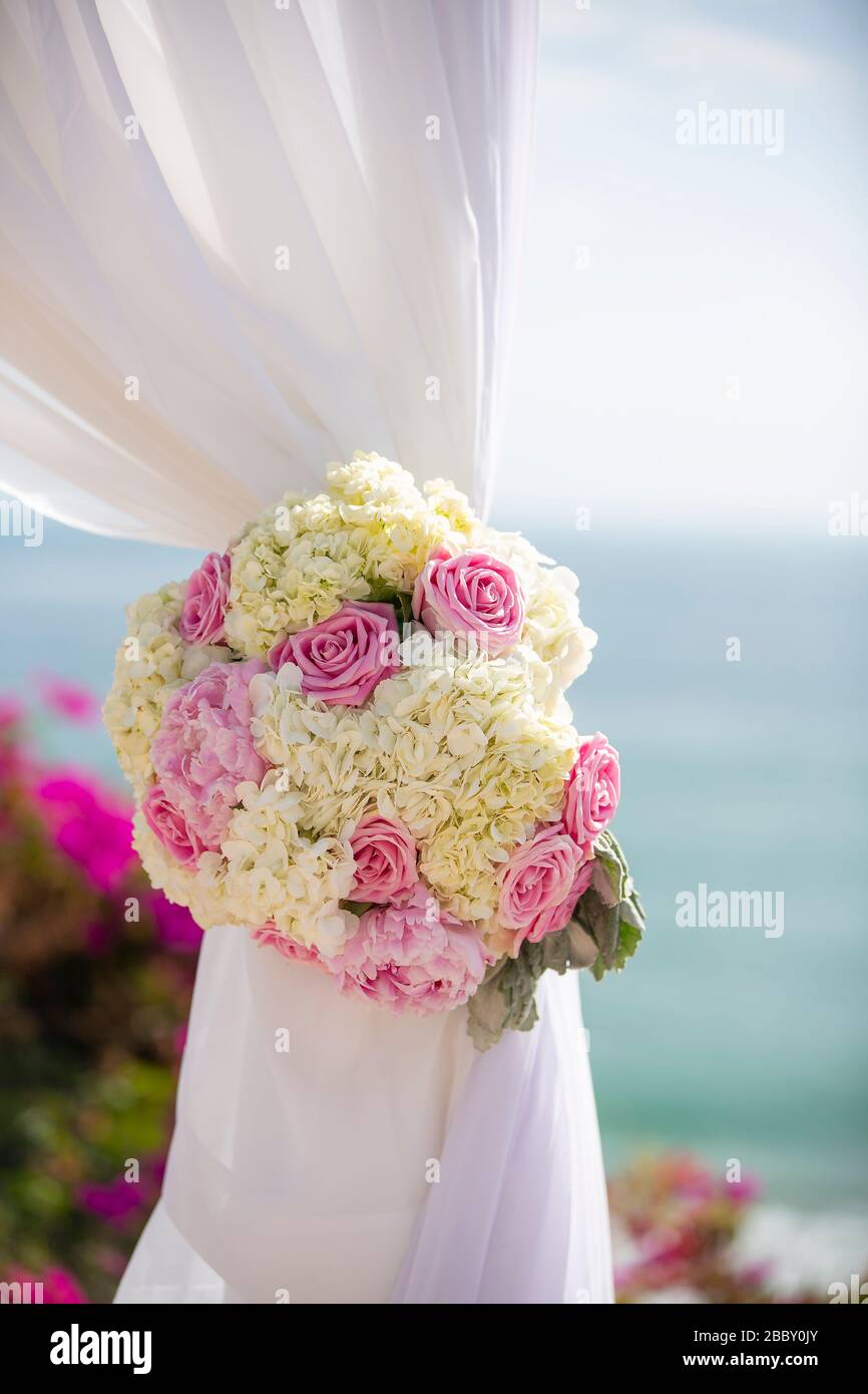 Wedding decor of pink and white roses tied to a white curtain for a ceremony Stock Photo