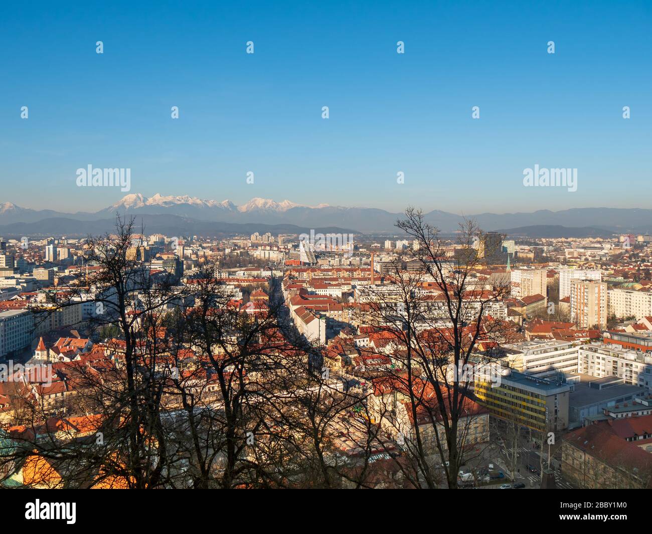 Ljubjlana Slovenia rooftop cityscape skyline panoramic view of old town architecture and Alps mountains, blue sky overhead. Stock Photo