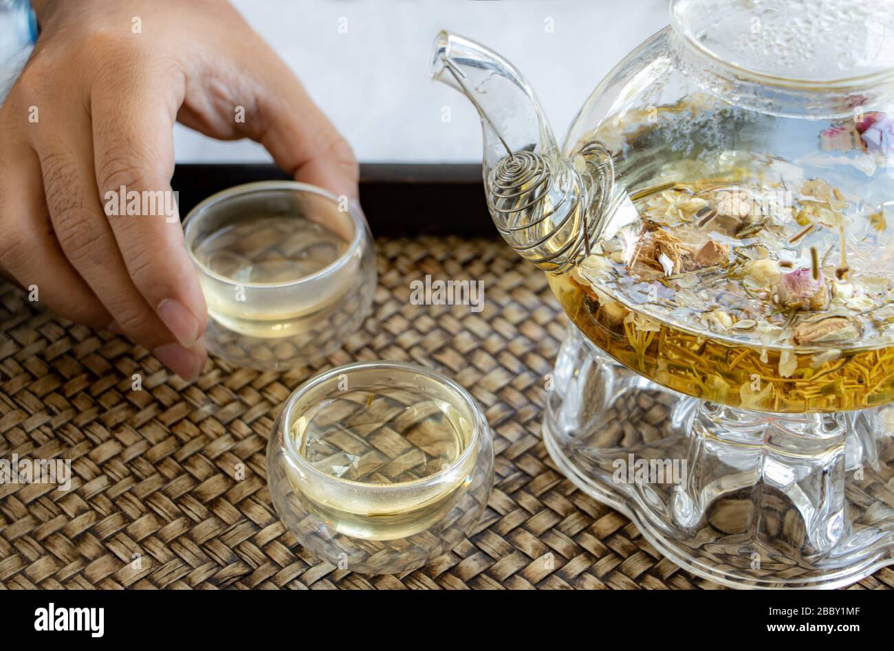 Herbal tea of drying flowers, close up. A teapot and cup with flowers tea on table. Stock Photo