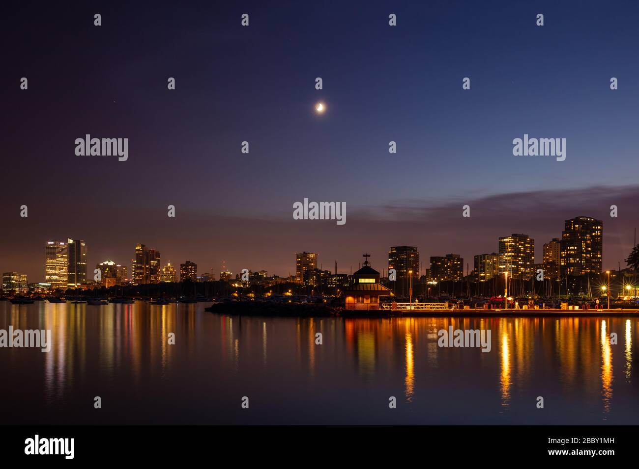 The Milwaukee skyline reflected in McKinley Marina at night with moonrise, Milwaukee, Wisconsin Stock Photo