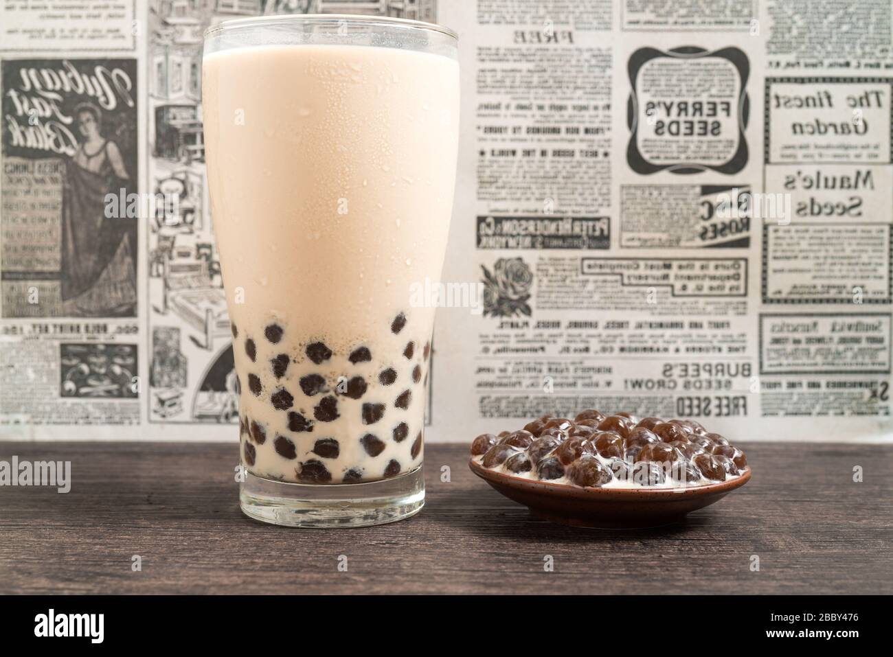 https://c8.alamy.com/comp/2BBY476/a-glass-cup-of-pearl-milk-tea-also-called-bubble-tea-and-a-plate-of-tapioca-ball-on-wooden-background-pearl-milk-tea-is-the-most-representative-dri-2BBY476.jpg