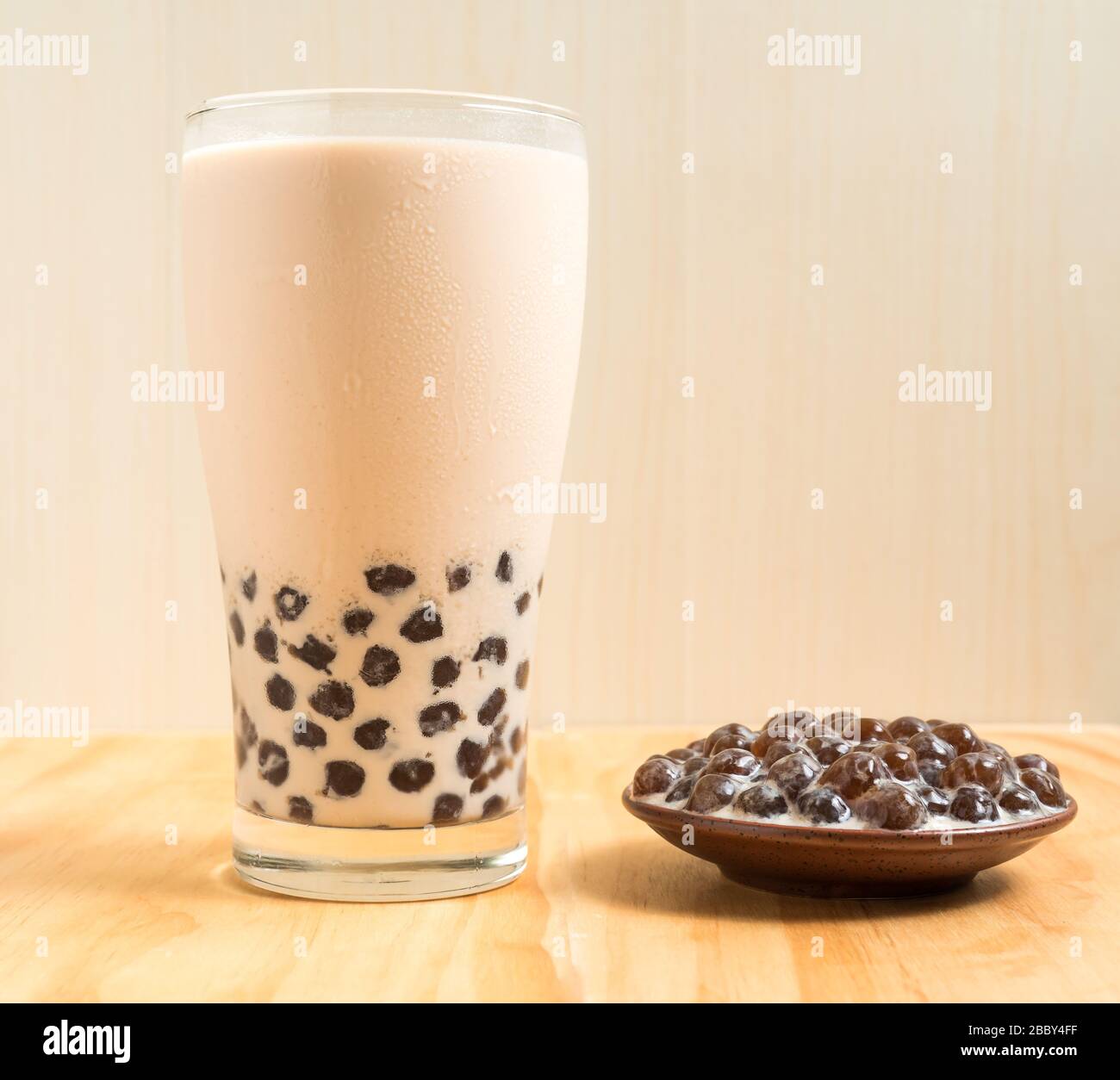 https://c8.alamy.com/comp/2BBY4FF/a-glass-cup-of-pearl-milk-tea-also-called-bubble-tea-and-a-plate-of-tapioca-ball-on-wooden-background-pearl-milk-tea-is-the-most-representative-dri-2BBY4FF.jpg