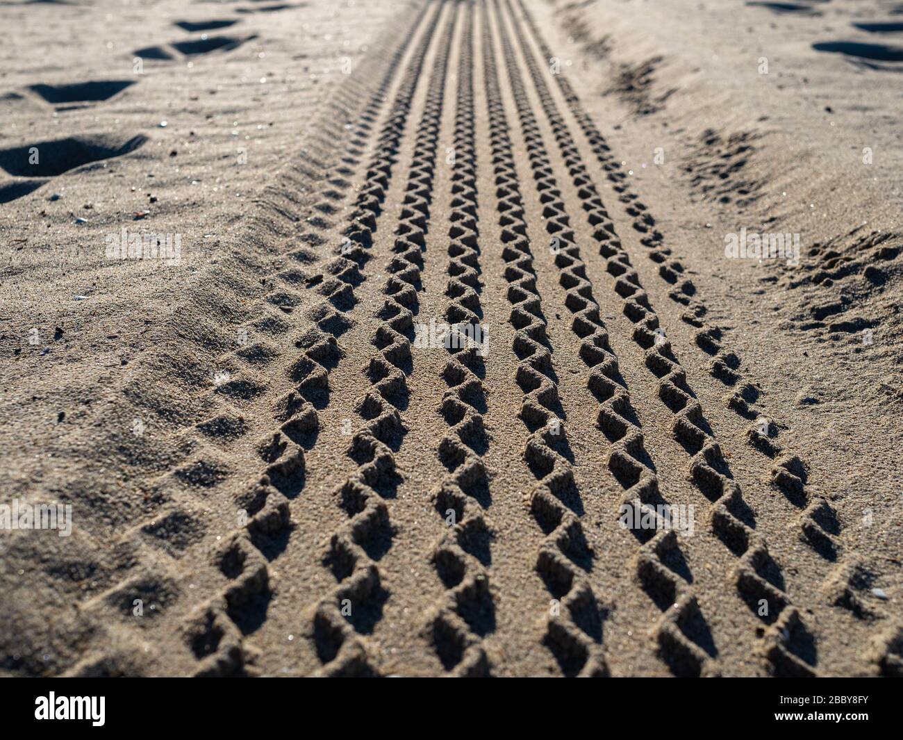 Close up view of tire tread marks on beach sand Stock Photo