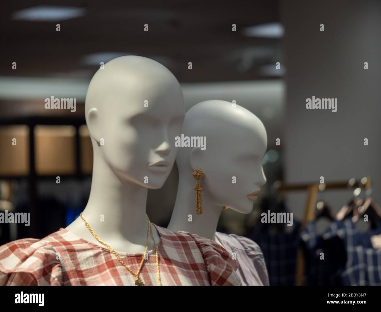 Two female mannequin posing in jewelry and blouses in department store