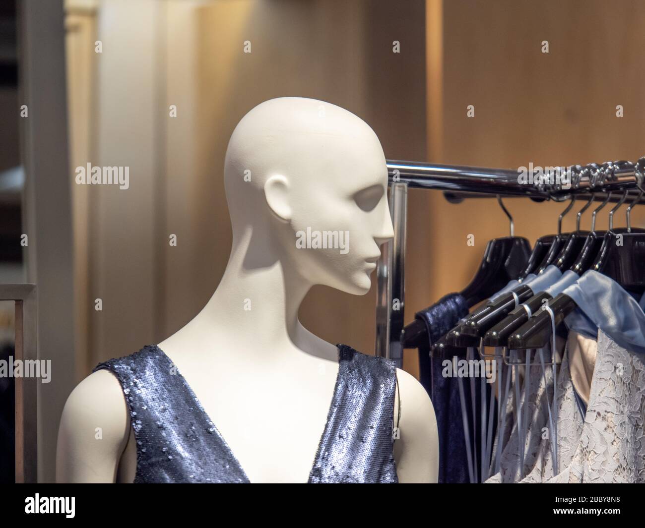 Female mannequin in dress next to clothing rack in department store