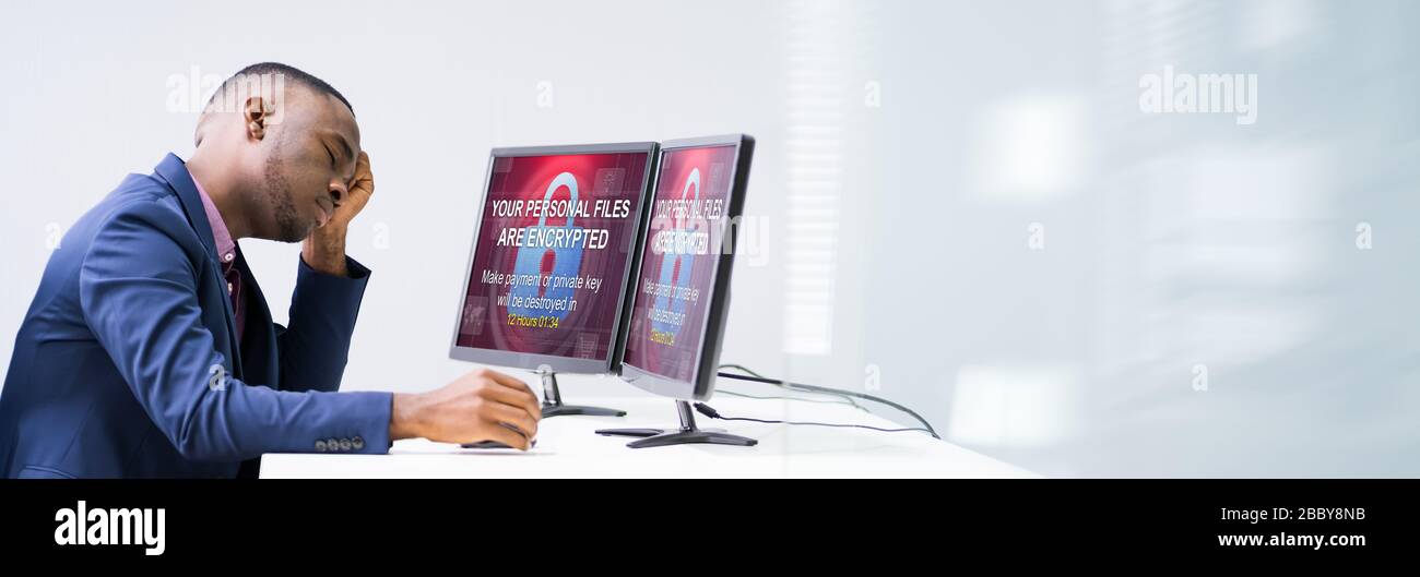 Worried Businessman Looking At Laptop With Ransomware Word On The Screen At The Workplace Stock Photo