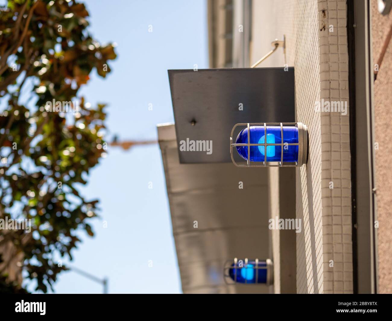 Blue caution safety lights affixed to building outside and positioned high Stock Photo