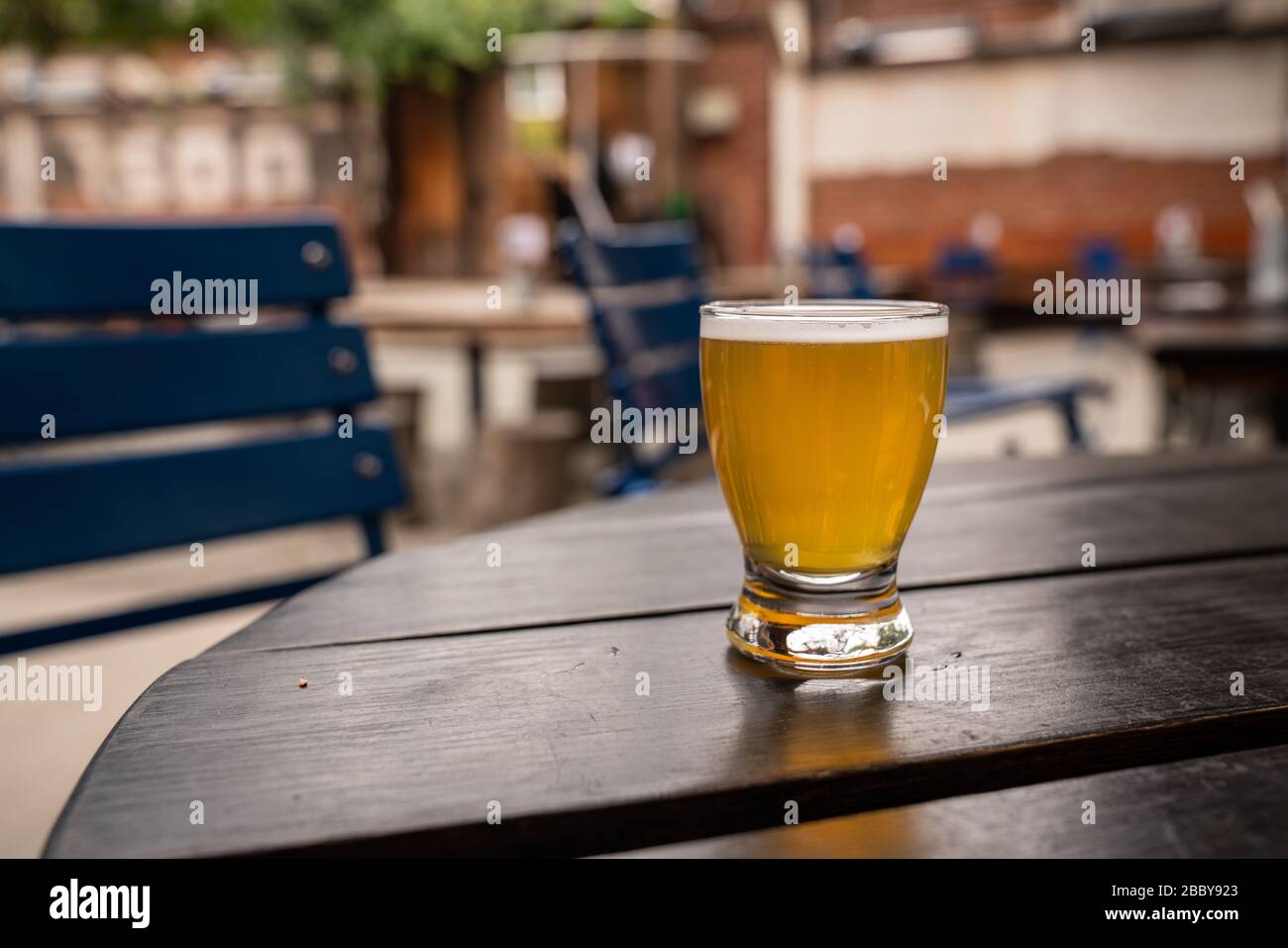 Golden beer in small tasting glass on table at outdoor restaurant Stock Photo