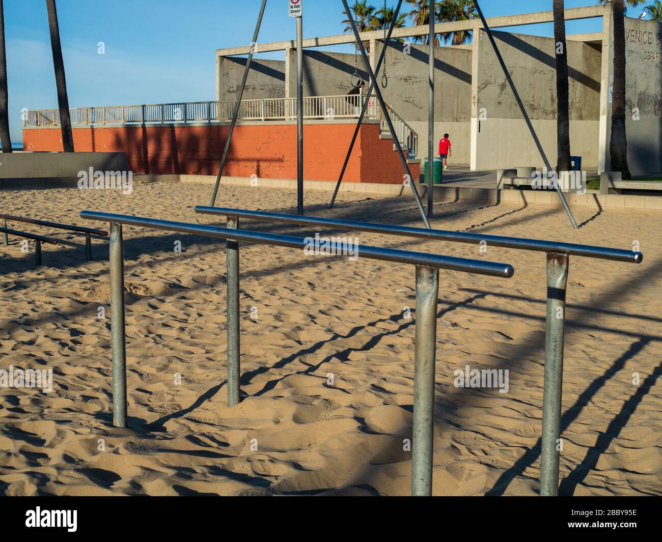 Gymnastics and exercise parallel bars on beach in outdoor gym with men exercising in the back Stock Photo