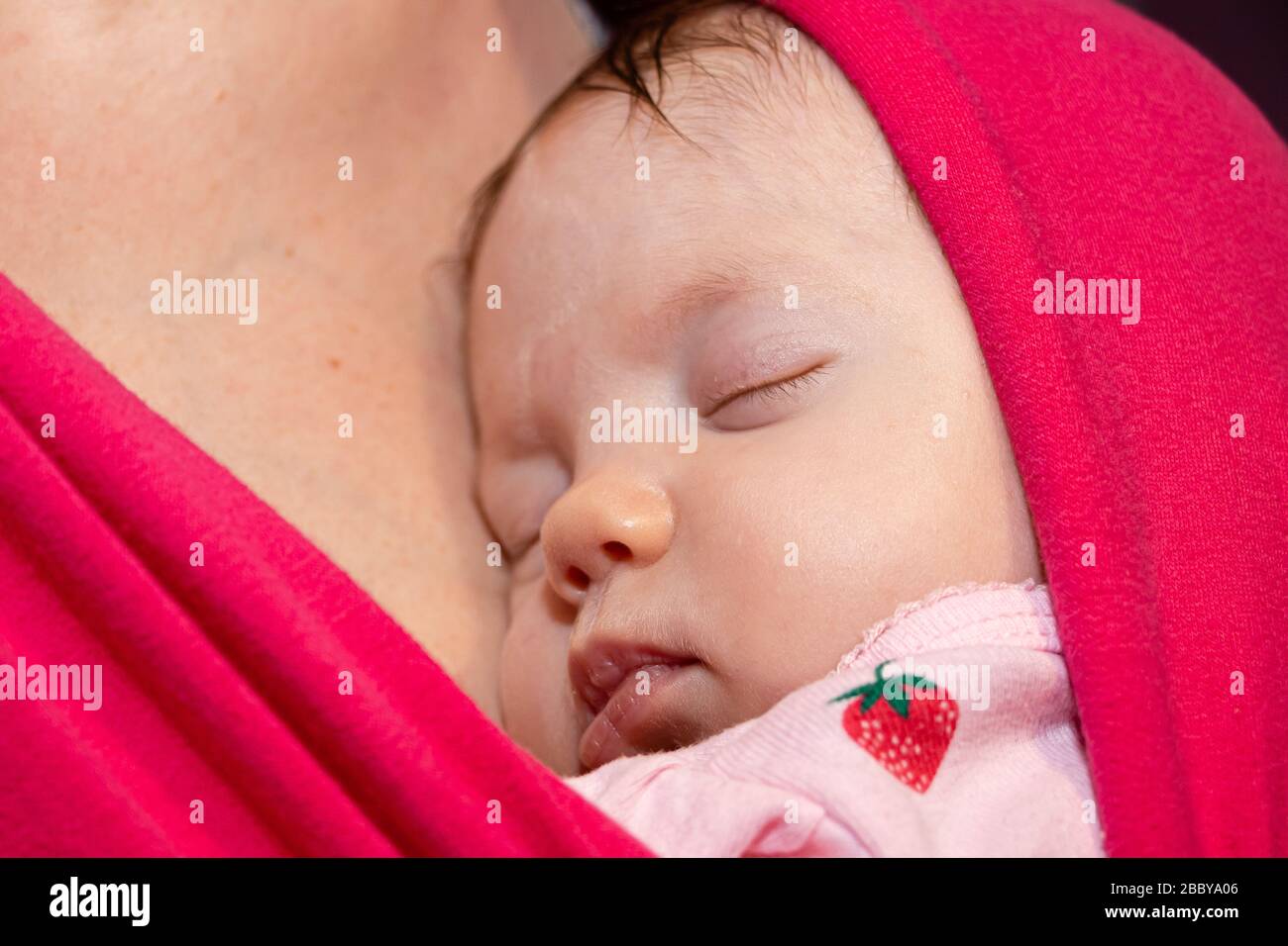 Baby is sleeping in sling, close up face. Newborn baby sleeping in a sling, in the embrace of