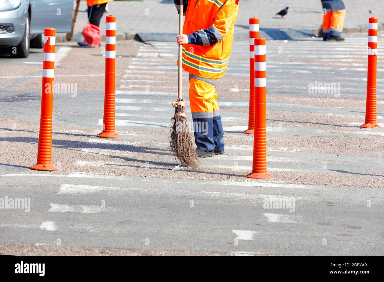 Route Rover Janitor A janitor in a bright orange uniform sweeps the street and removes ...