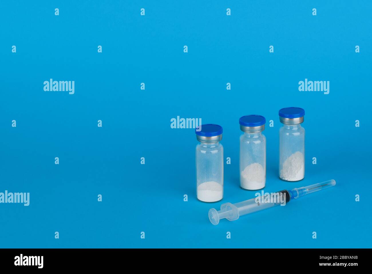 Bottles with antibiotic solution in a row and syringe on a blue