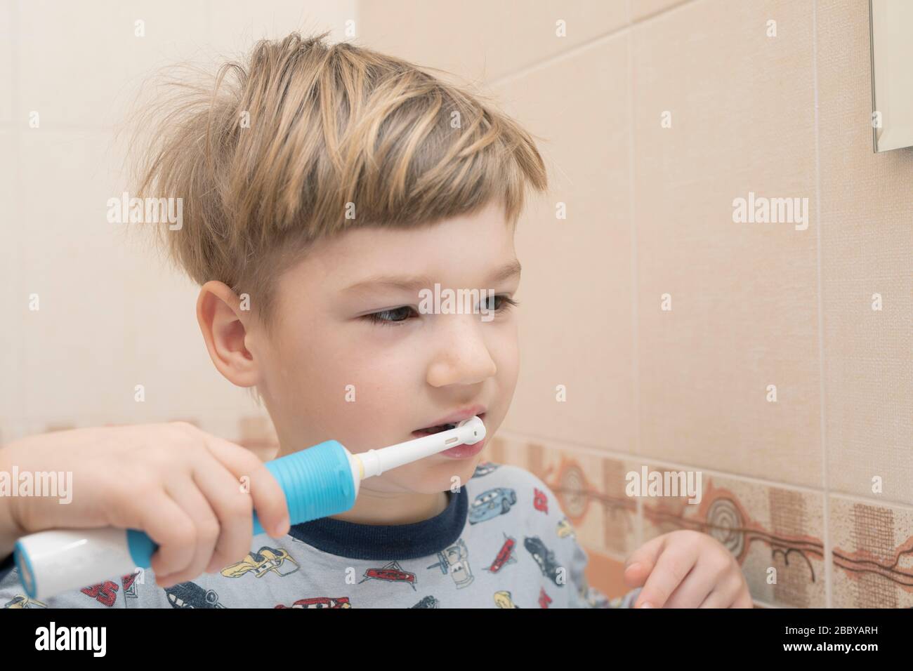 little boy cleaning teeth with electric toothbrush on bathroom