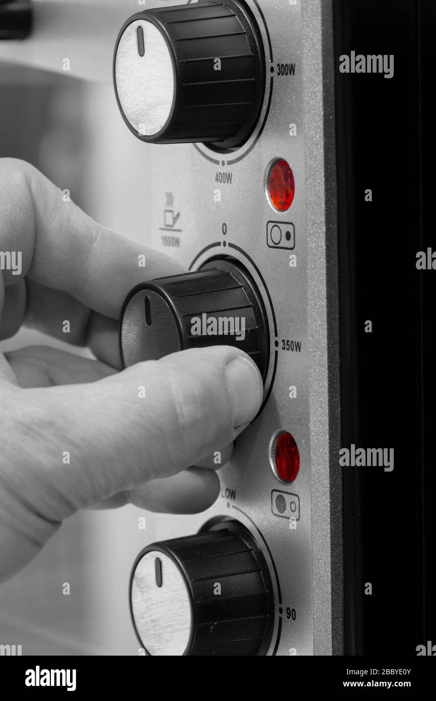 Man setting the power setting on an electric oven grill by turning a