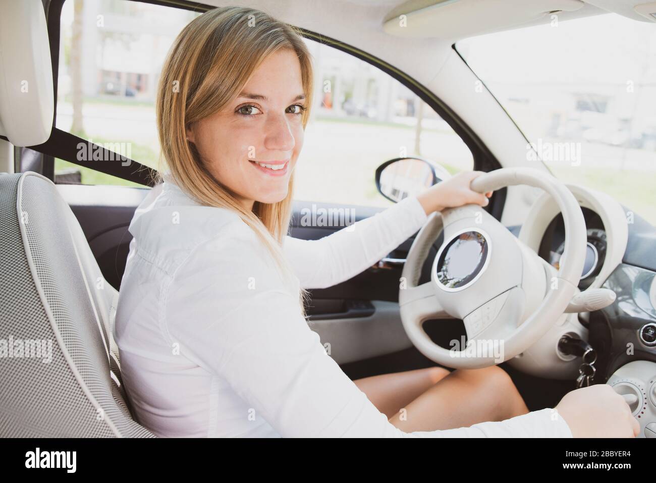 Personable young woman with nice laugh is sitting in a new car Stock Photo