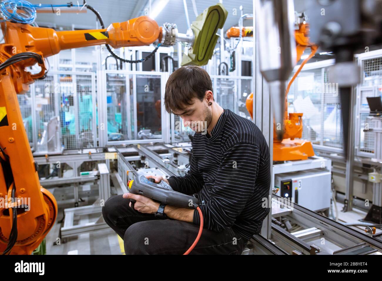 Programmer programming automatic robot arms in automotive smart factory, industrial concept Stock Photo