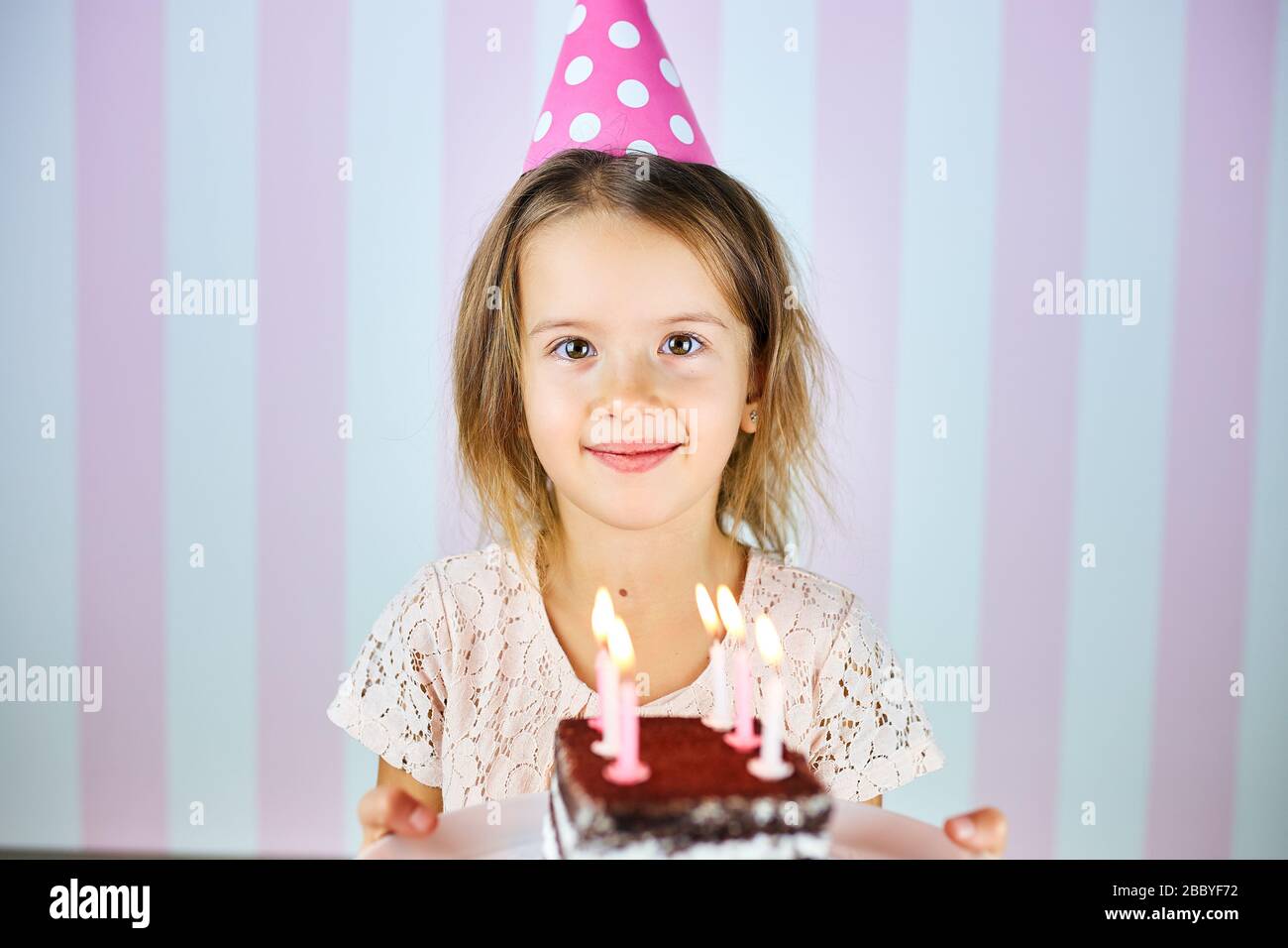 Little blonde girl smiling in birthday pink cap, a chocolate birthday ...