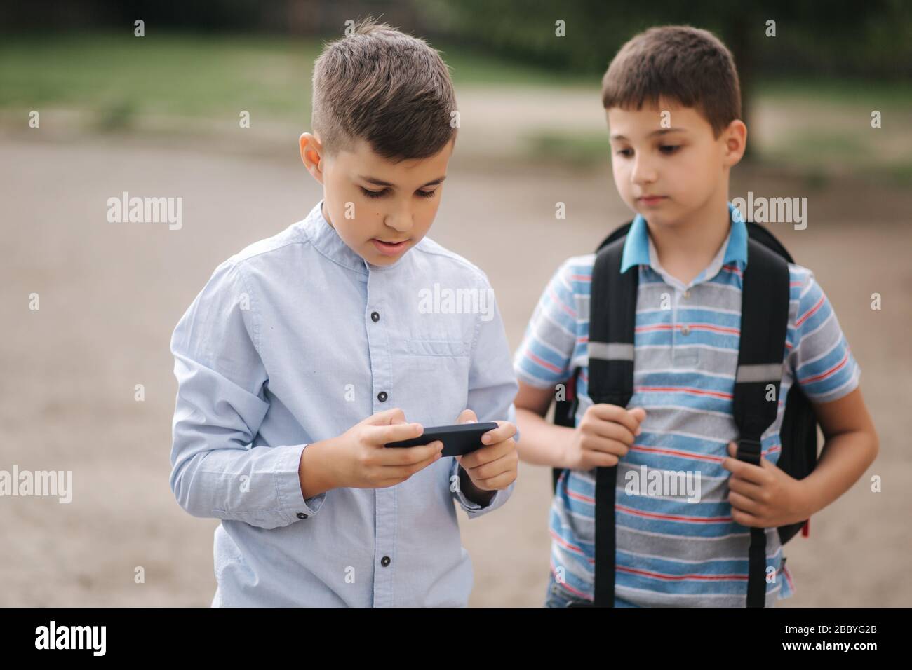 Two boys plays online games in quarantine. Young boys smile and use phone.  One look how play another Stock Photo - Alamy