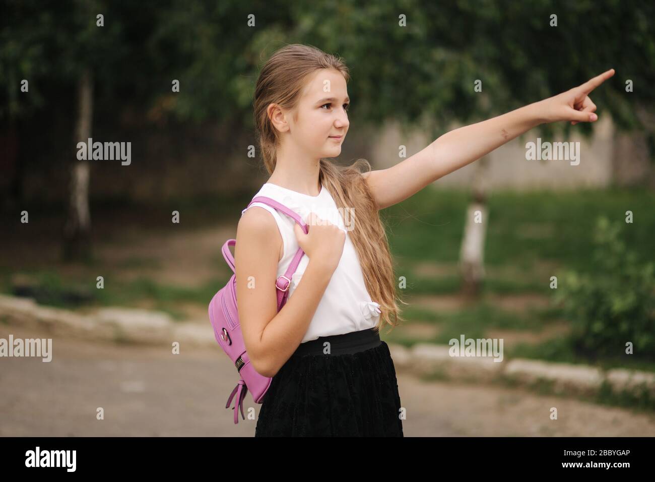 Young girl walking in the park with backpack Stock Photo - Alamy