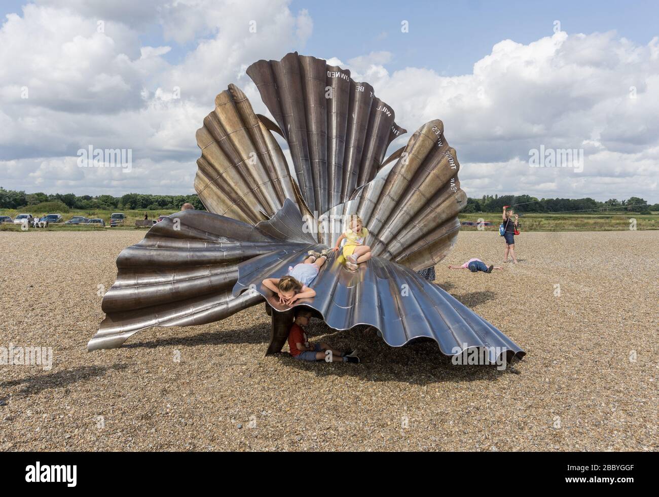 Children playing on the Scallop sculpture on Aldeburgh Beach, Suffolk, UK; 2003 by Maggi Hamblin and dedicated to the composer Benjamin Britten Stock Photo
