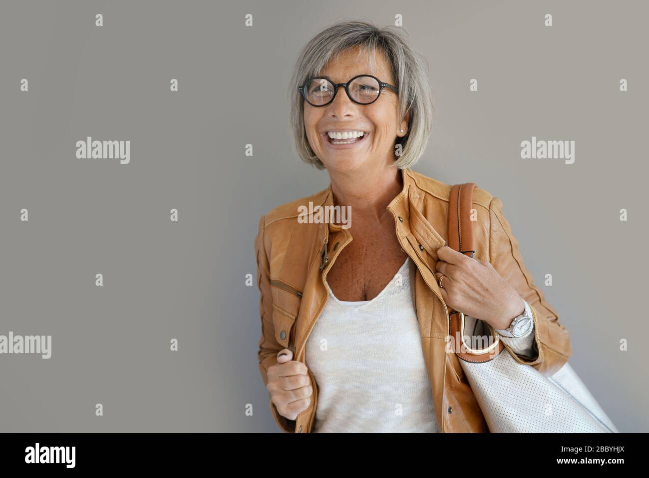 Modern mature woman standing on grey background Stock Photo - Alamy
