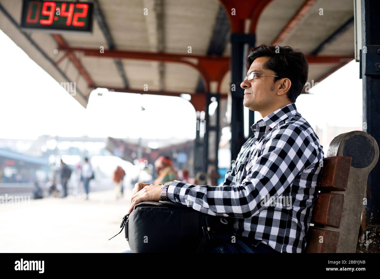 Man with bag waiting at railroad station platform Stock Photo