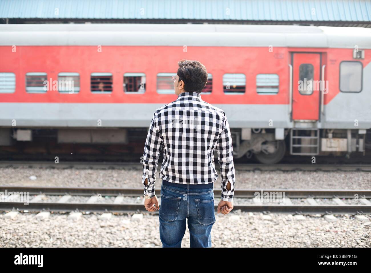 Rear view of man standing at railroad station Stock Photo