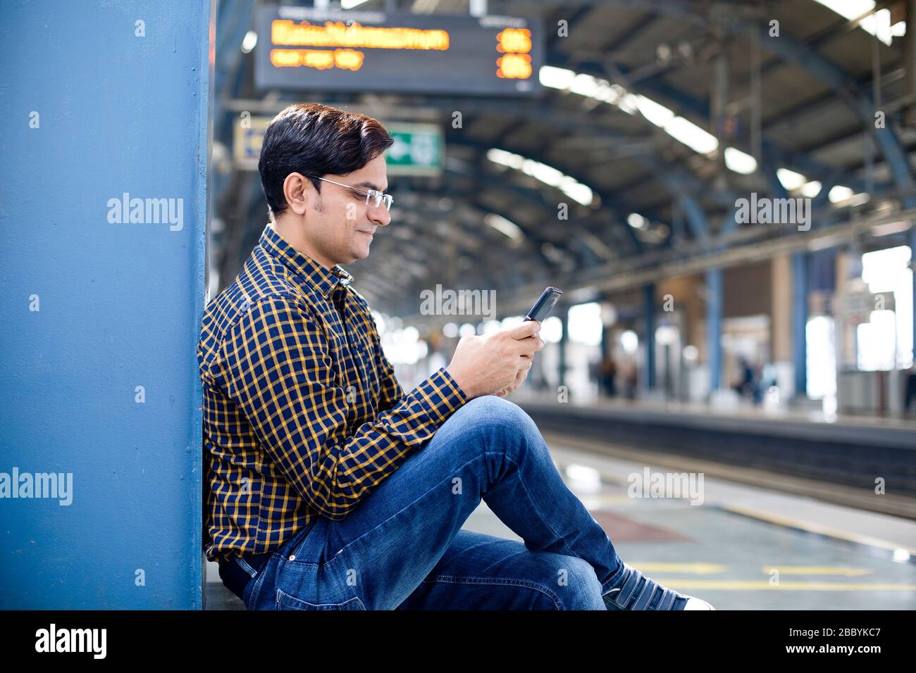 Man using mobile phone at railroad station platform Stock Photo