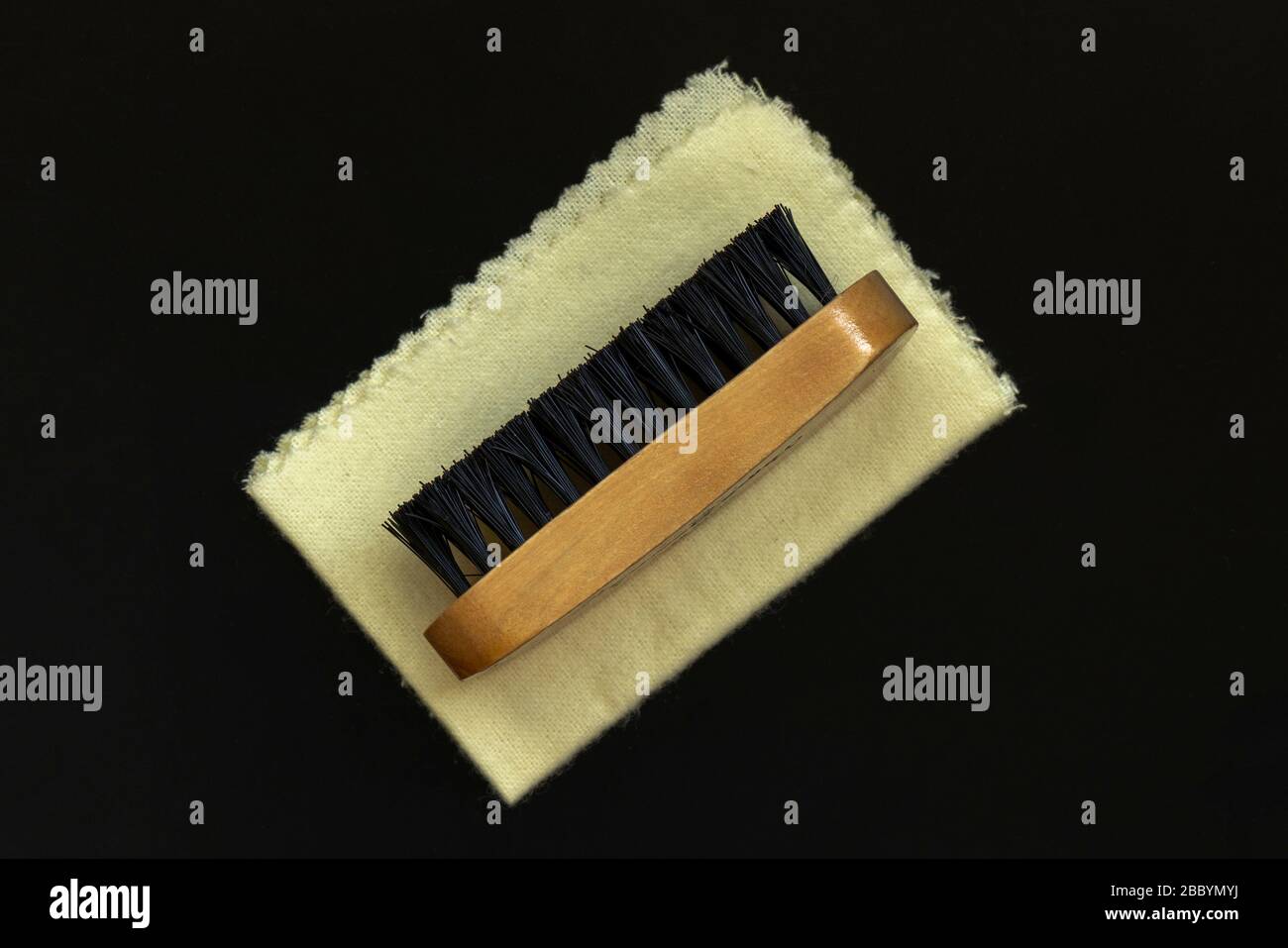 Brush and soft cloth as boot care kit or shoe shine kit accessories on black background from above. Stock Photo