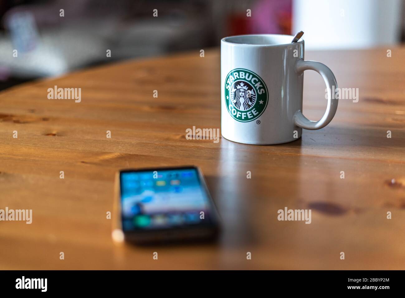 Starbucks glass coffee mug with mobile phone on wooden table Stock