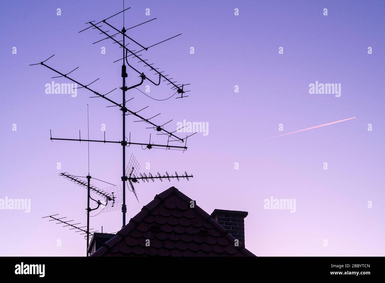 House roof with antenna and sky with contrails, Munich, Upper Bavaria, Bavaria, Germany Stock Photo