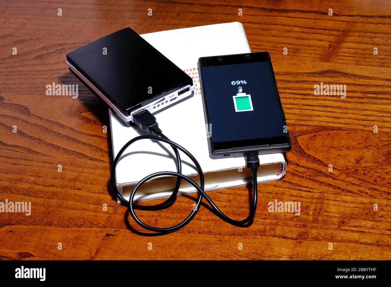 Smartphone in charge with a powerbank on  a book Stock Photo